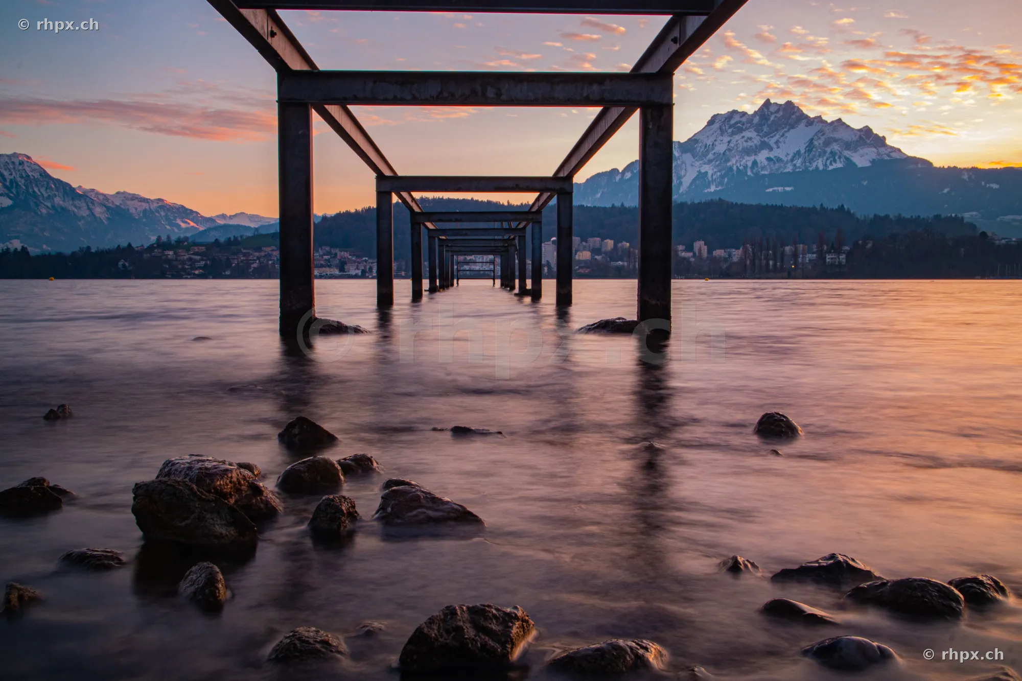 View through a steel pier in Lake Lucerne towards Mount Pilatus at sunset