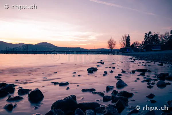 Steine im flachen Wasser am Ufer des Vierwaldstättersees bei Sonnenuntergang
