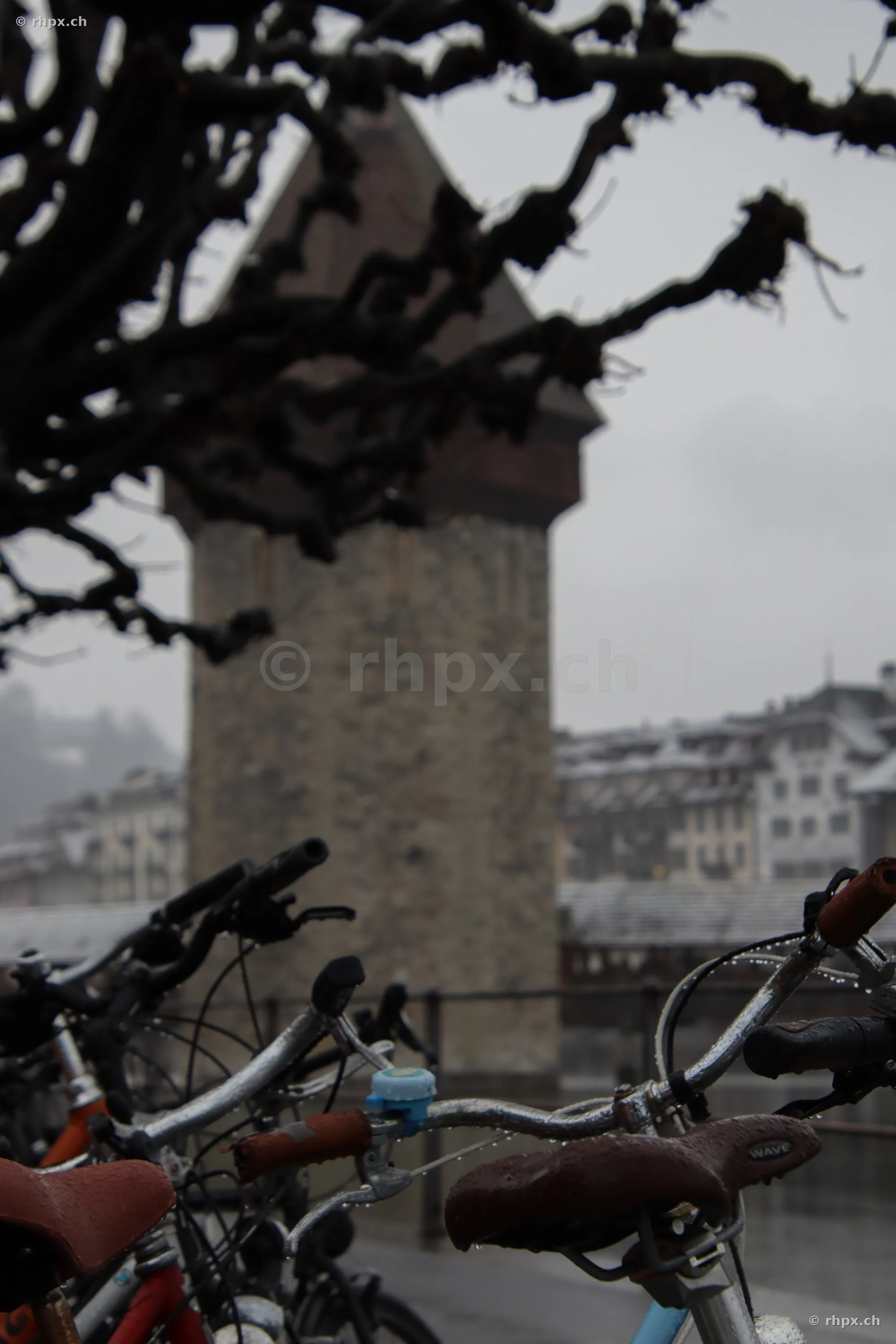 The Water Tower in Lucerne behind bicycle handlebars in rainy weather