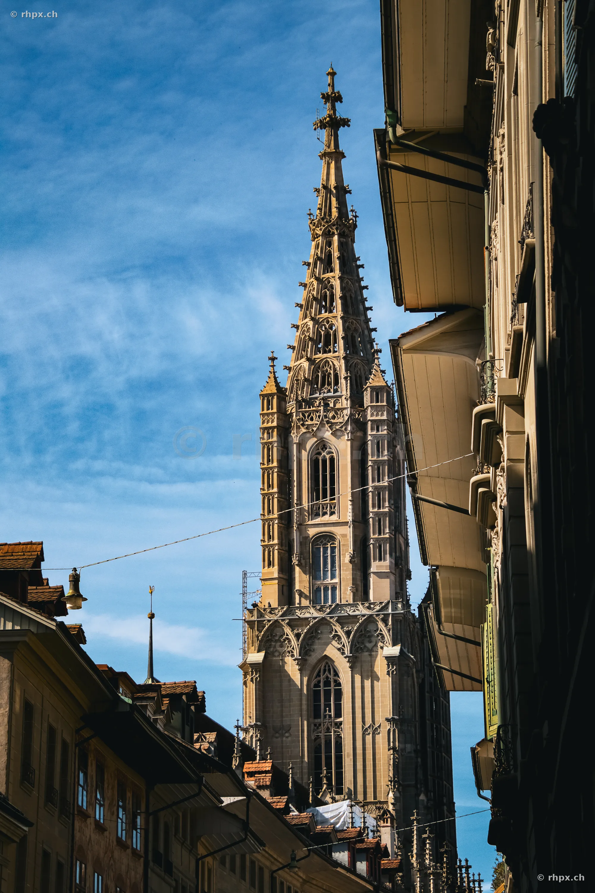 Blick auf den Turm des Berner Münsters aus einer engen Gasse der Berner Altstadt