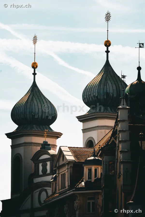Detailansicht der Zwiebeltürme der Jesuitenkirche in Luzern vor einem hellen Himmel