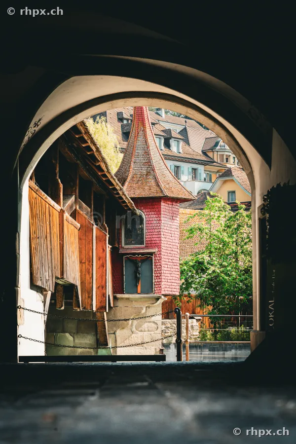 Blick durch einen steinernen Torbogen auf einen Turm der Museggmauer in Luzern