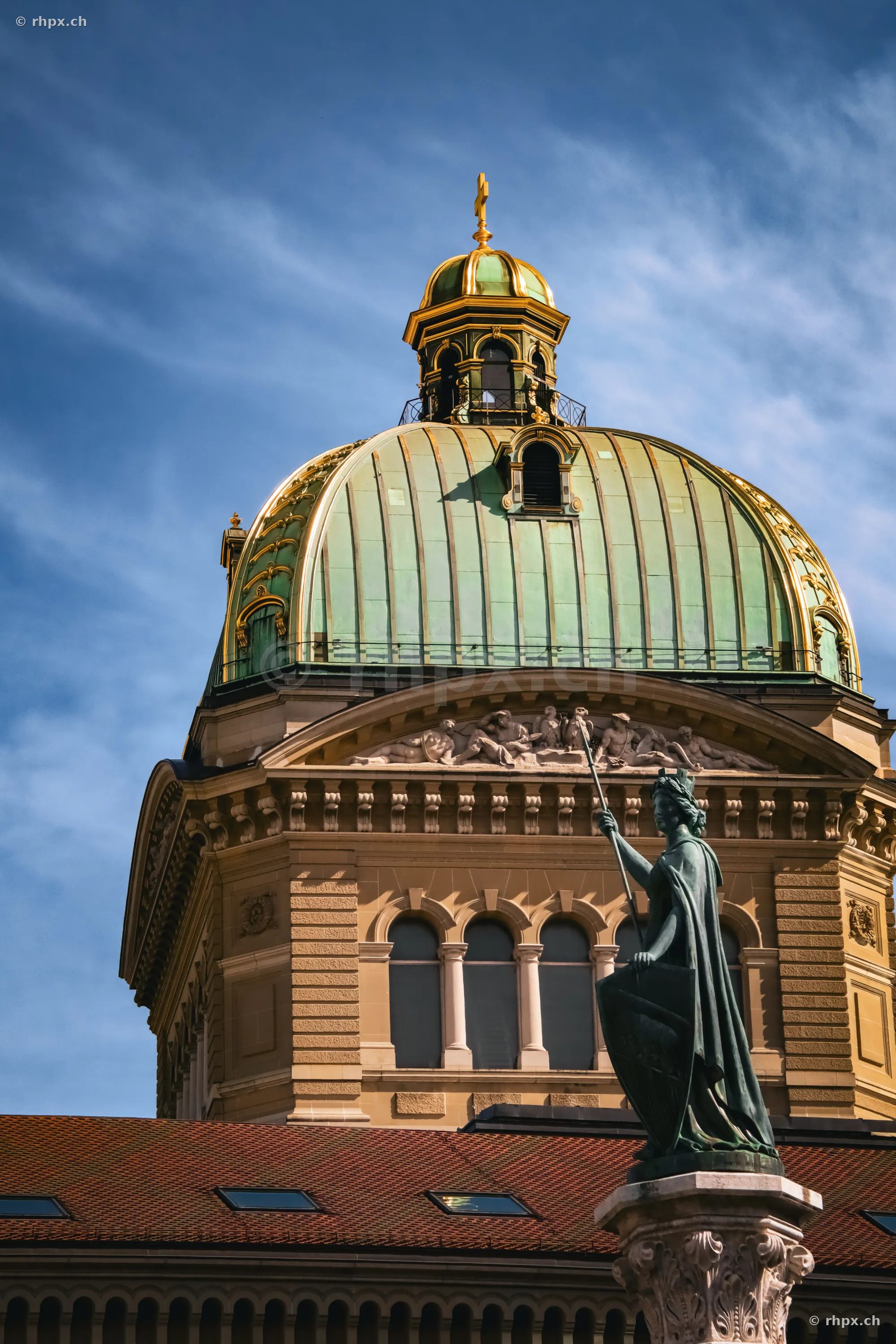 Swiss Parliament dome and statue in Bern against blue sky