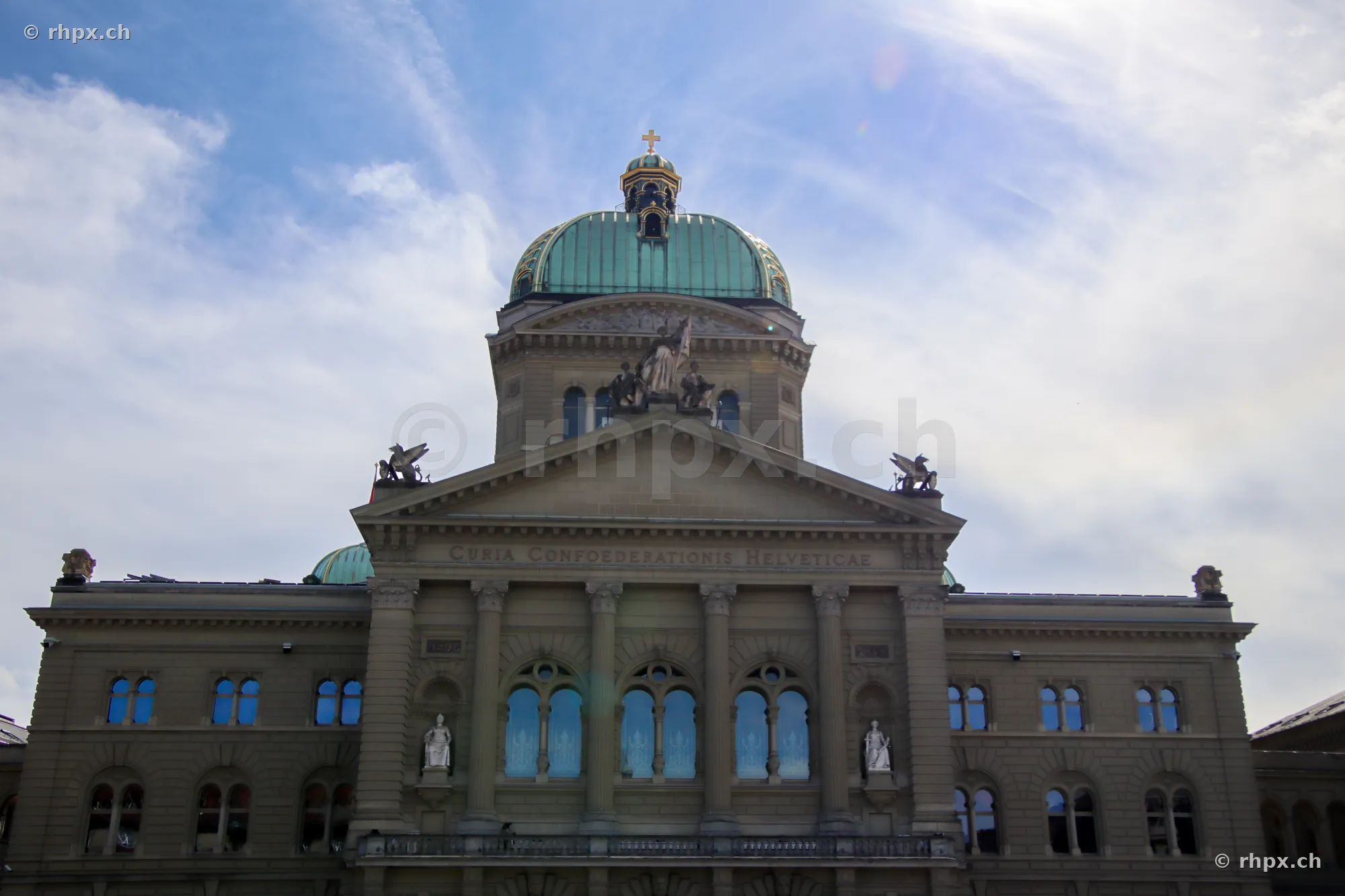 Central front view of the Bern Federal Palace with dome under a cloudy sky