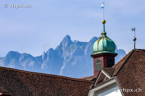 The copper-roofed tower of the Hofkirche in Lucerne in front of the massive Mount Pilatus.