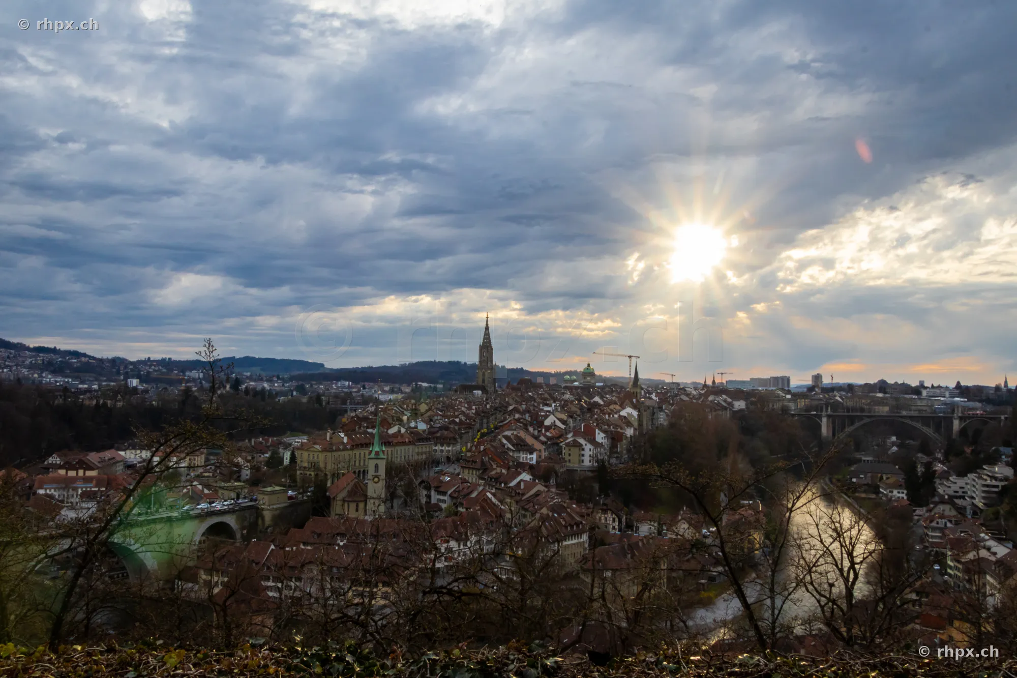 Panoramablick auf die Berner Altstadt mit Aare und Kirchenschiff bei bewölktem Himmel