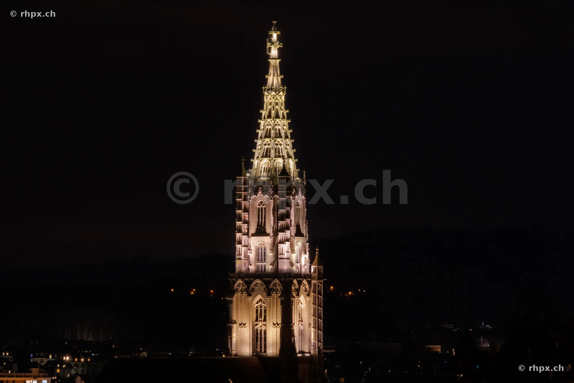 Der beleuchtete Turm des Berner Münsters vor dunklem Nachthimmel