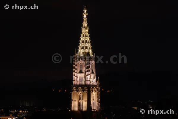 Der beleuchtete Turm des Berner Münsters vor dunklem Nachthimmel