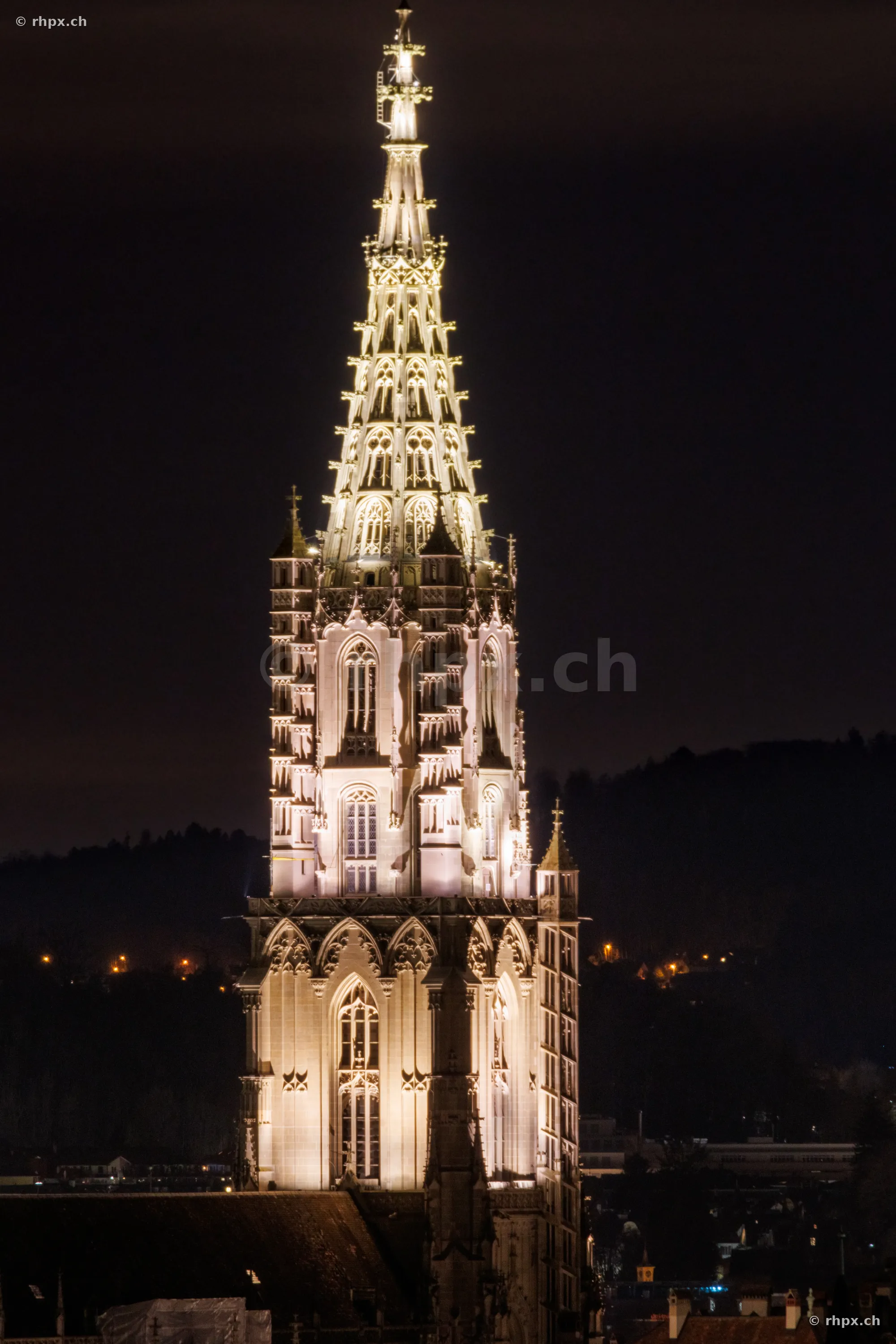 Detailaufnahme vom beleuchteten Turm des Berner Münsters bei Nacht