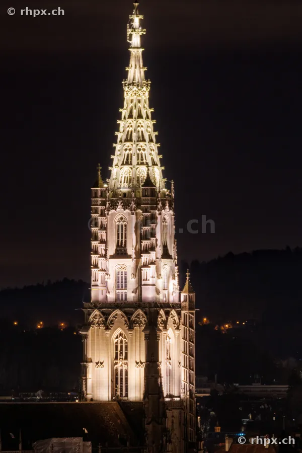 Detailaufnahme vom beleuchteten Turm des Berner Münsters bei Nacht