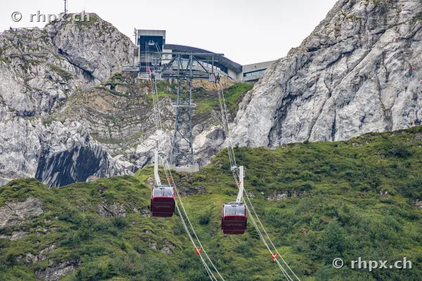 Zwei rote Kabinen der Luftseilbahn Dragon Ride am Pilatus vor felsiger Bergkulisse