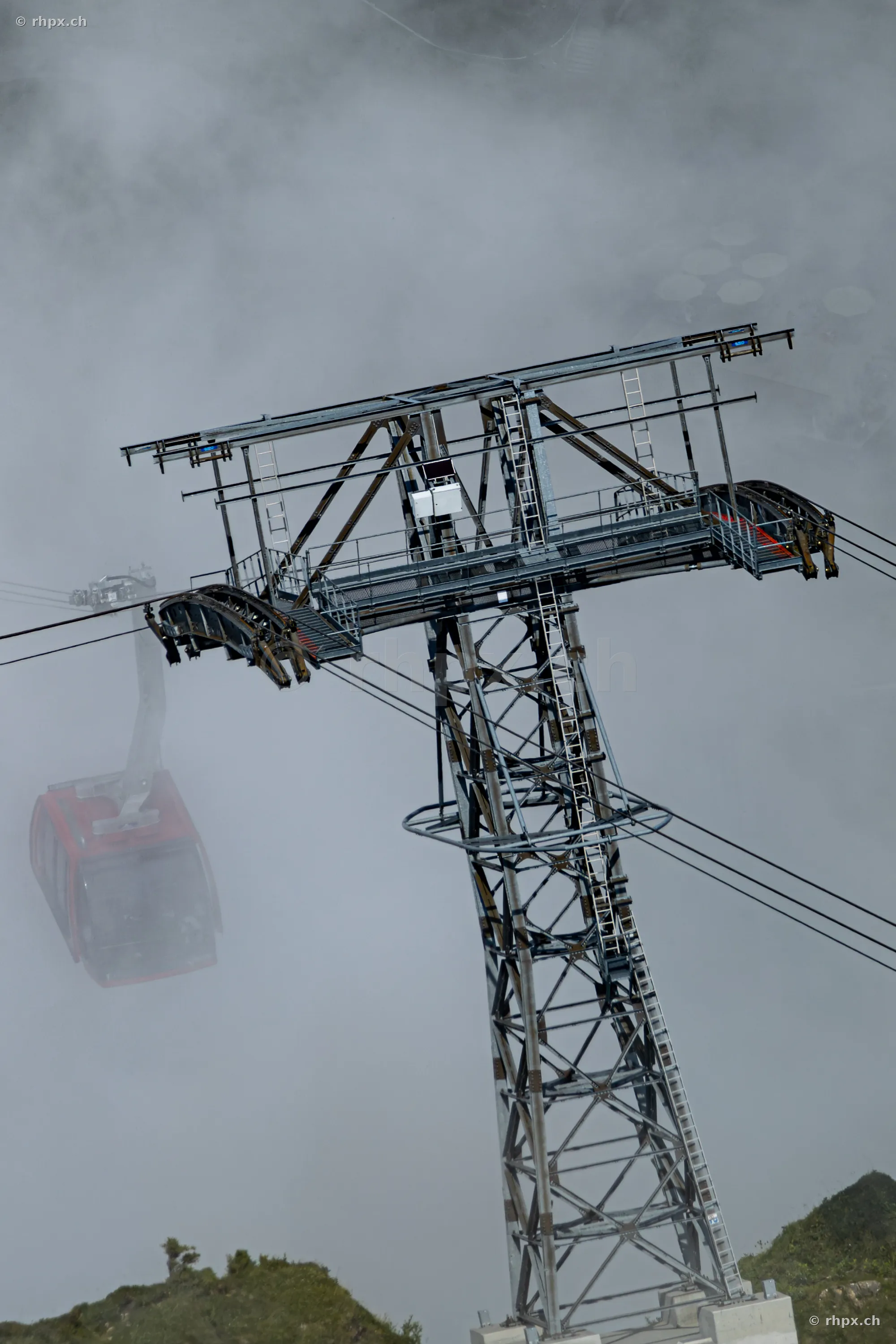 Stahlstütze der Pilatusbahn mit einer roten Gondel im dichten Nebel