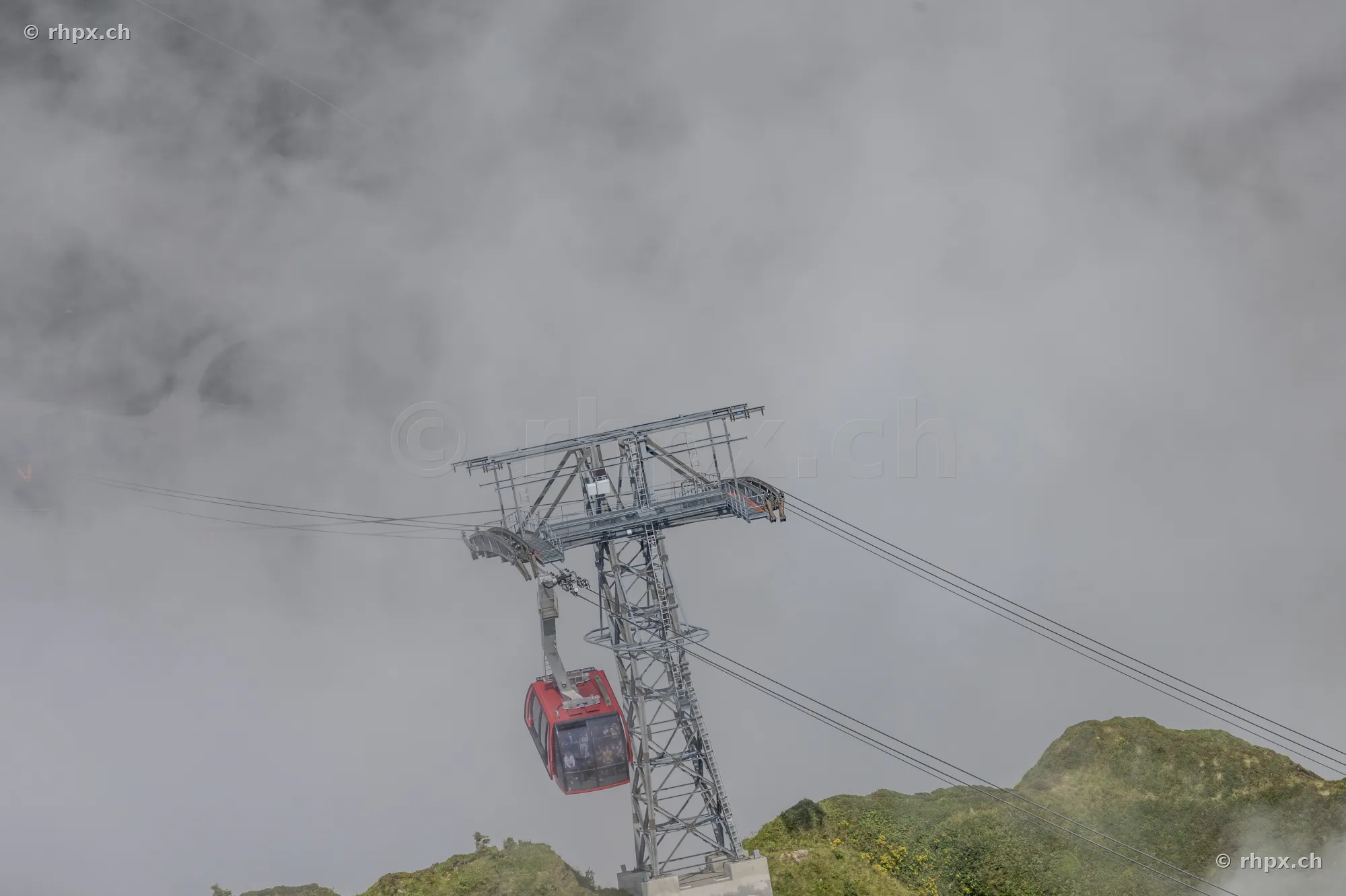 Red cabin of the Pilatus cableway on a steel pylon in foggy mountain landscape