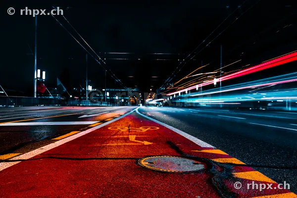 Nachtaufnahme einer Strasse in Luzern mit langbelichteten Lichtspuren auf dem Radstreifen