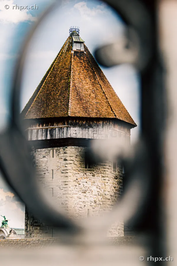 Blick auf den Wasserturm Luzern durch die Öffnung eines metallenen Geländers