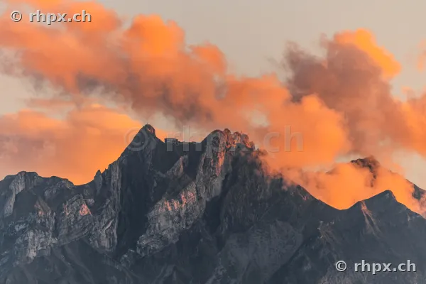 Der Gipfel des Pilatus bei Luzern in der Abenddämmerung mit orangerot beleuchteten Wolken.