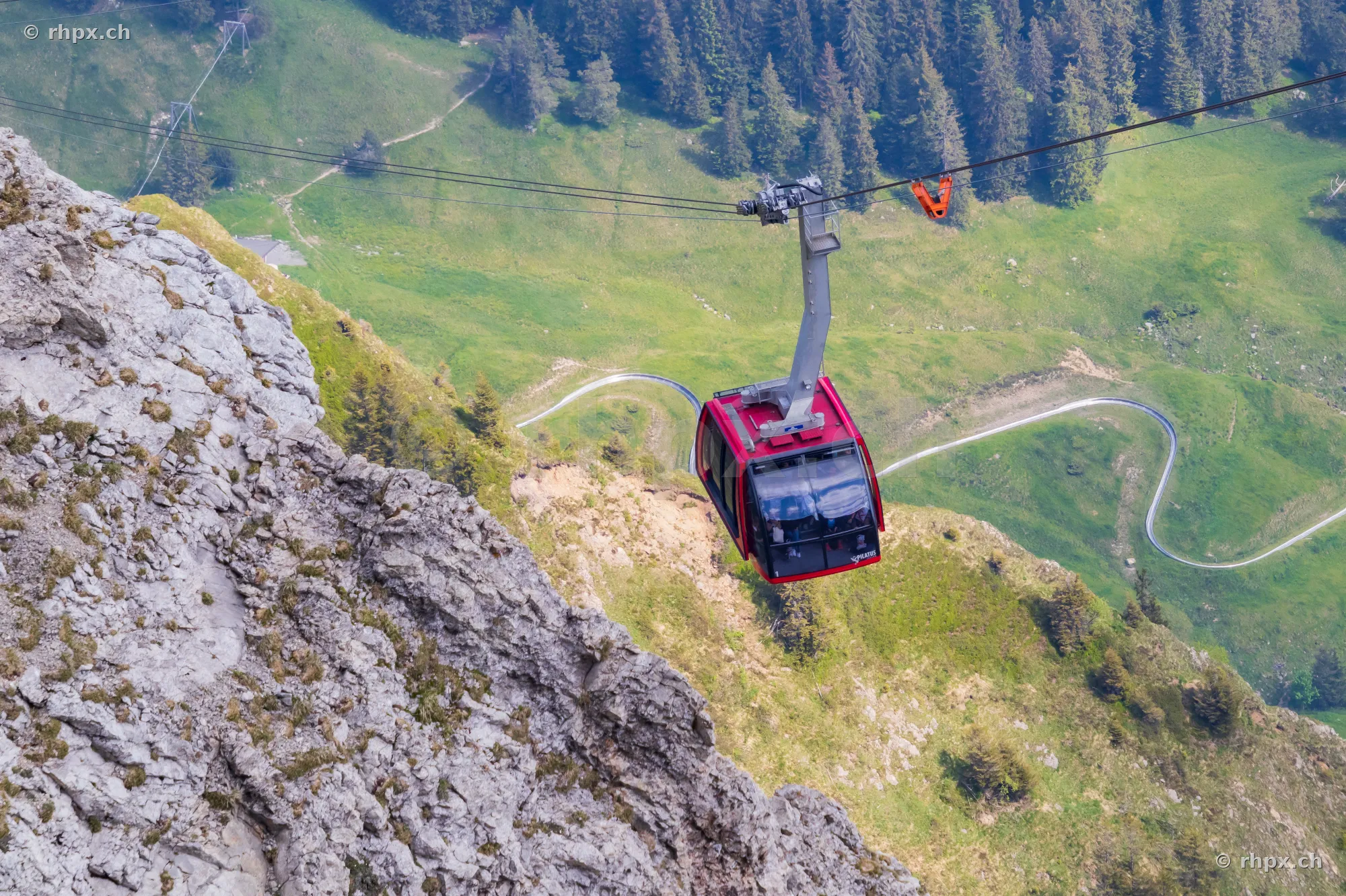 Red cable car gondola at Mount Pilatus in front of steep rock