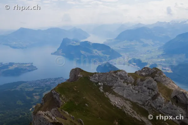 Blick von einem felsigen Berggipfel des Pilatus hinunter auf den Vierwaldstättersee und die umliegende Zentralschweizer Alpenlandschaft