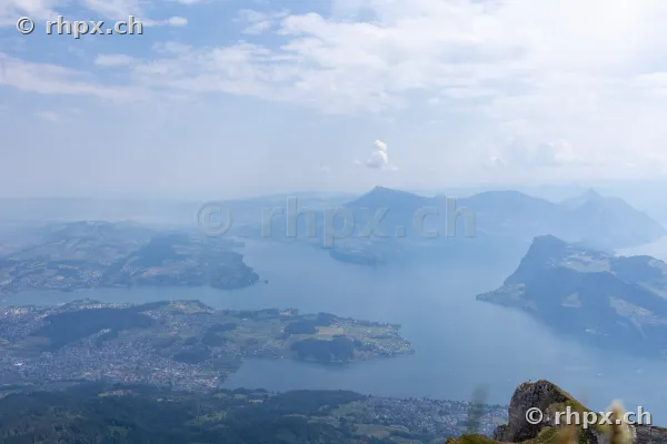 Blick von der Höhe des Pilatus auf den Vierwaldstättersee und die umliegende Berglandschaft bei hellem Tageslicht.