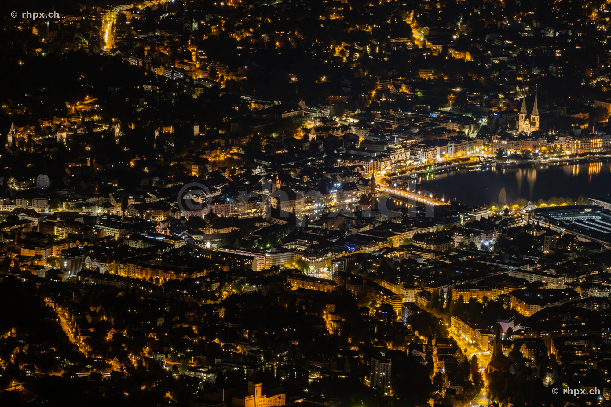 Nächtliche Luftaufnahme der Stadt Luzern mit dem Vierwaldstättersee und beleuchteten Strassen