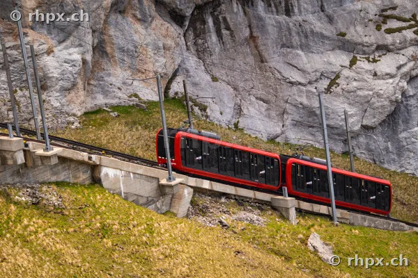 Roter Triebwagen der Pilatusbahn bei der Fahrt durch eine steile Felswand