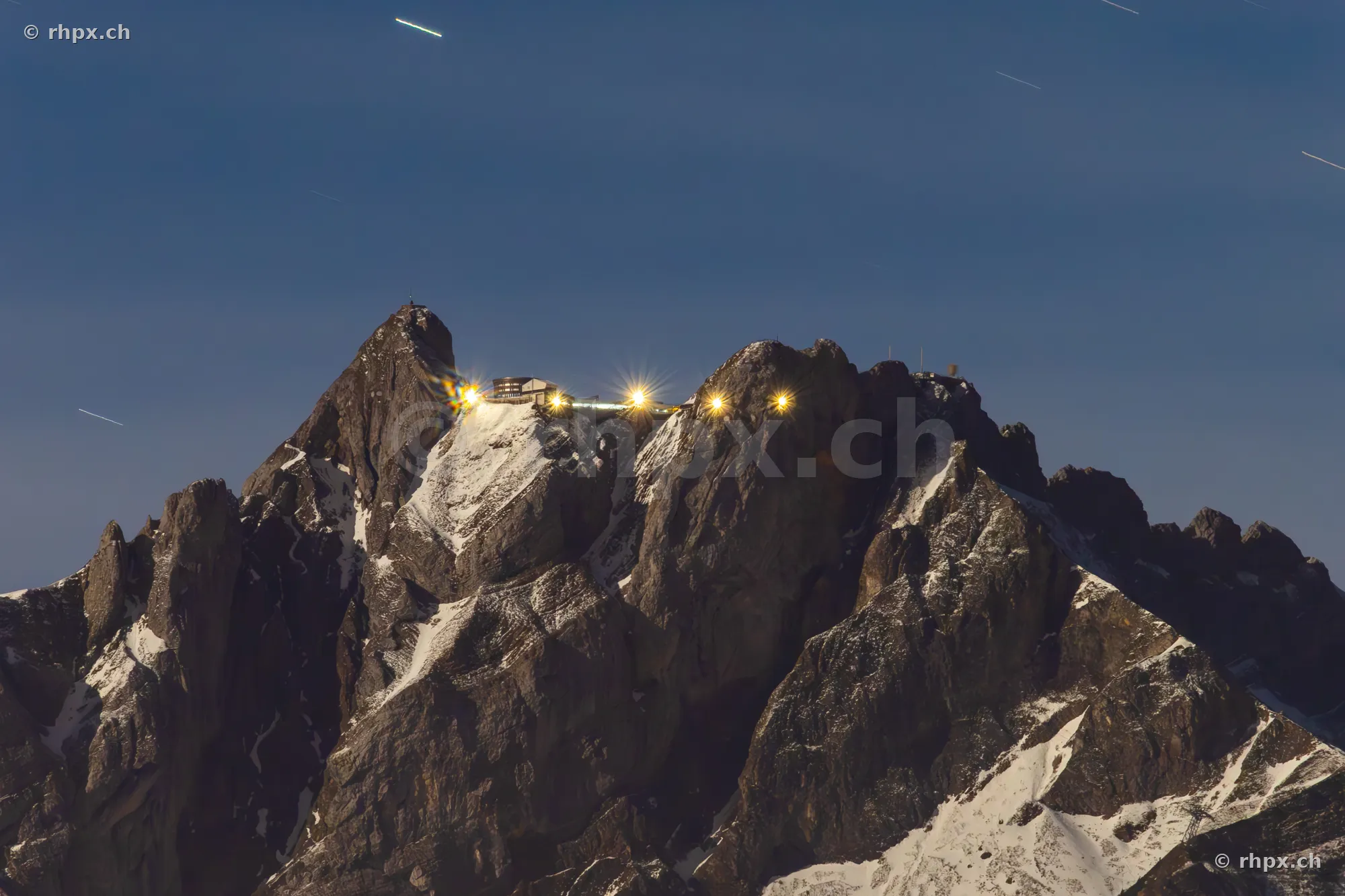 The summit of Mount Pilatus with the illuminated hotel building against the night sky
