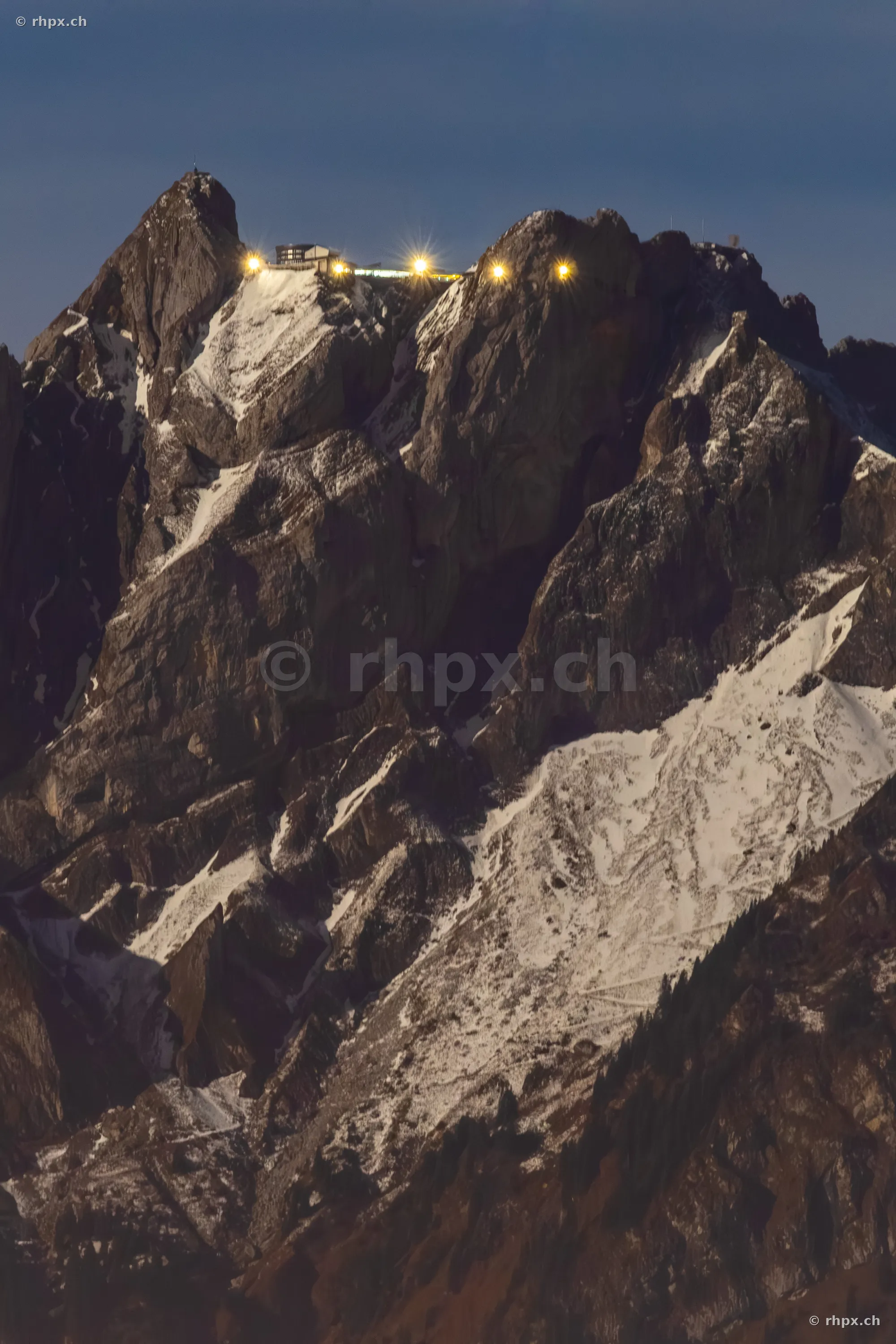 Summit area of Mount Pilatus with illuminated hotel and mountain station at dusk