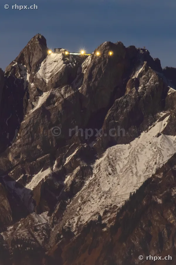 Gipfelbereich des Pilatus mit beleuchtetem Hotel und Bergstation in der Dämmerung