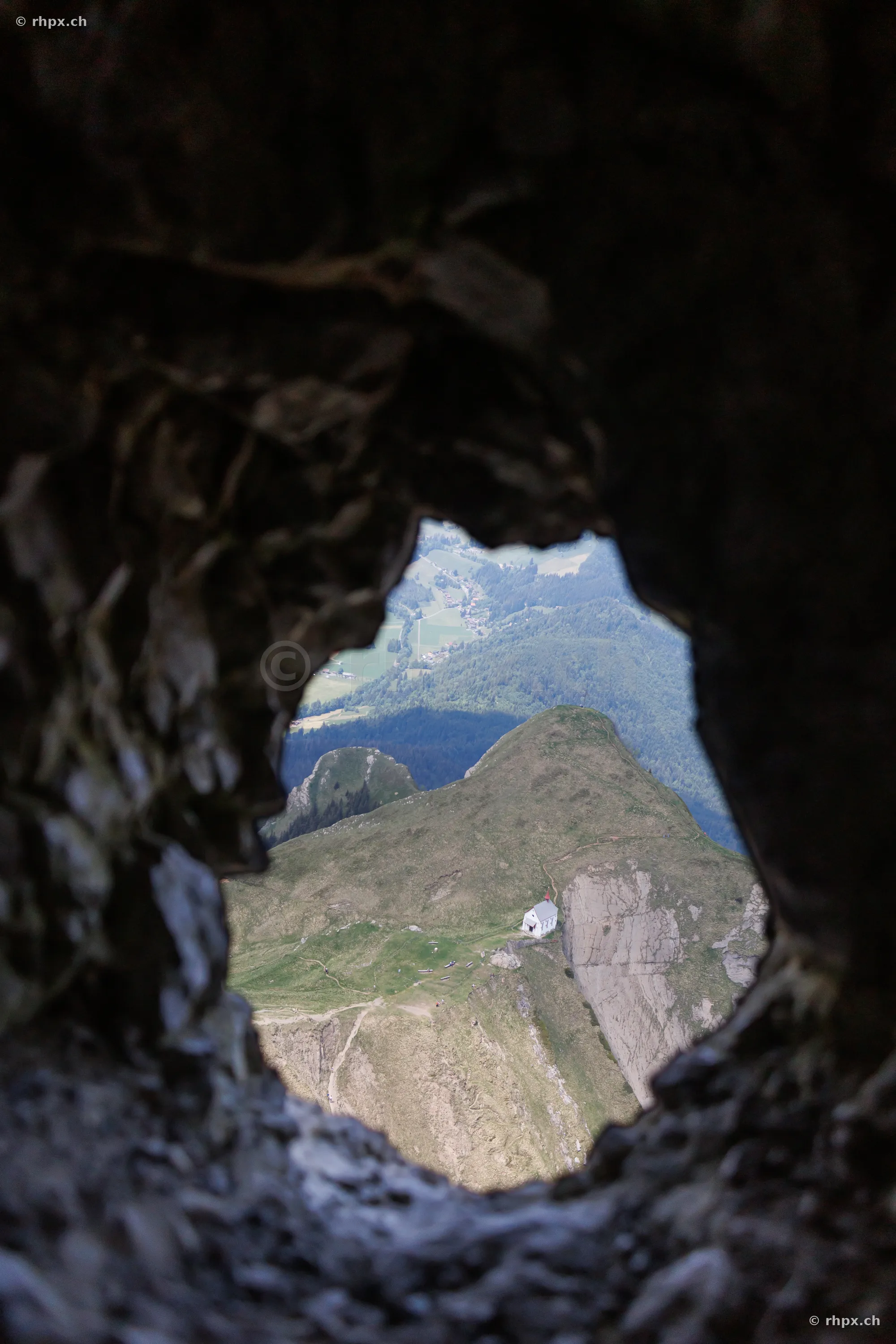 View through a hole in the rock looking down at the small chapel below the Pilatus massif in Central Switzerland