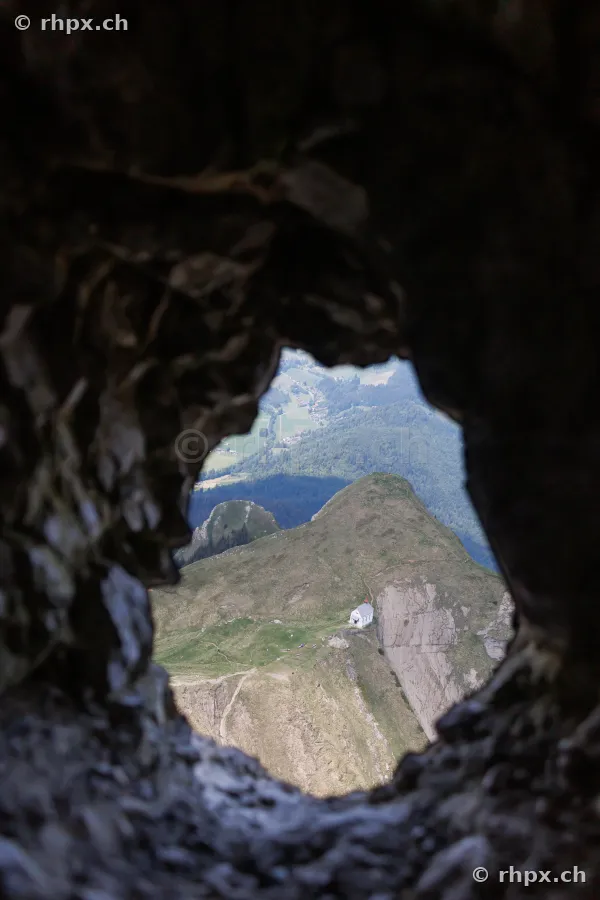 View through a hole in the rock looking down at the small chapel below the Pilatus massif in Central Switzerland
