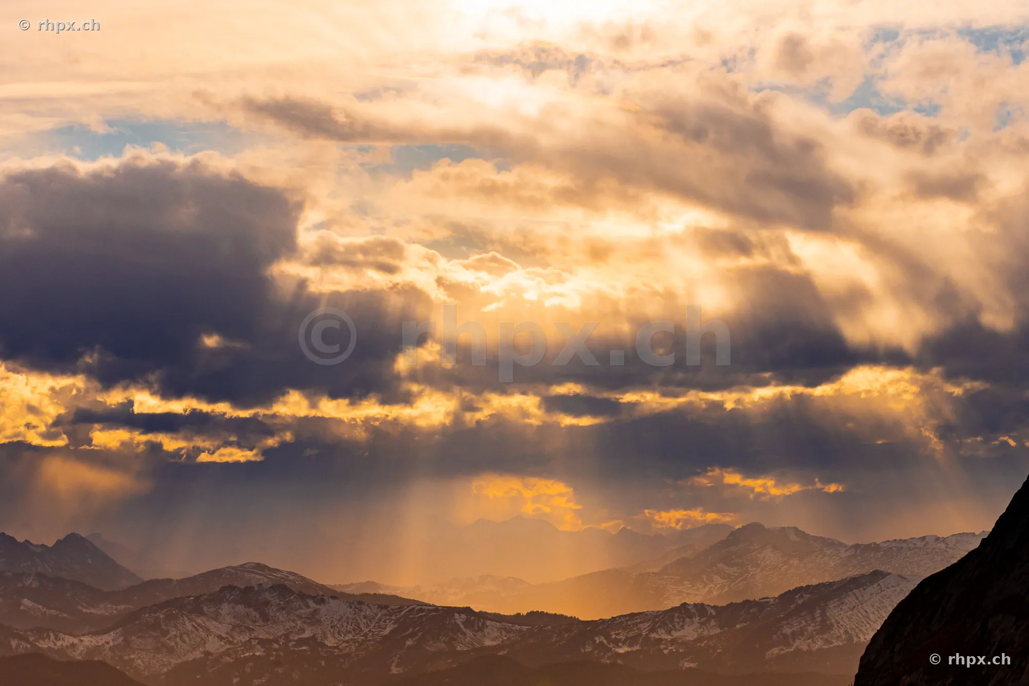 View of the Pilatus massif with sunbeams through the cloud cover