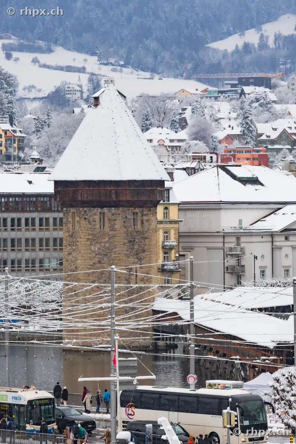 Snow-covered Wasserturm of the Chapel Bridge in Lucerne with surrounding cityscape