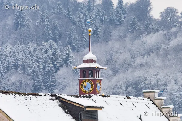 Snow-covered tower of the Musegg wall in front of a wooded hillside in Lucerne