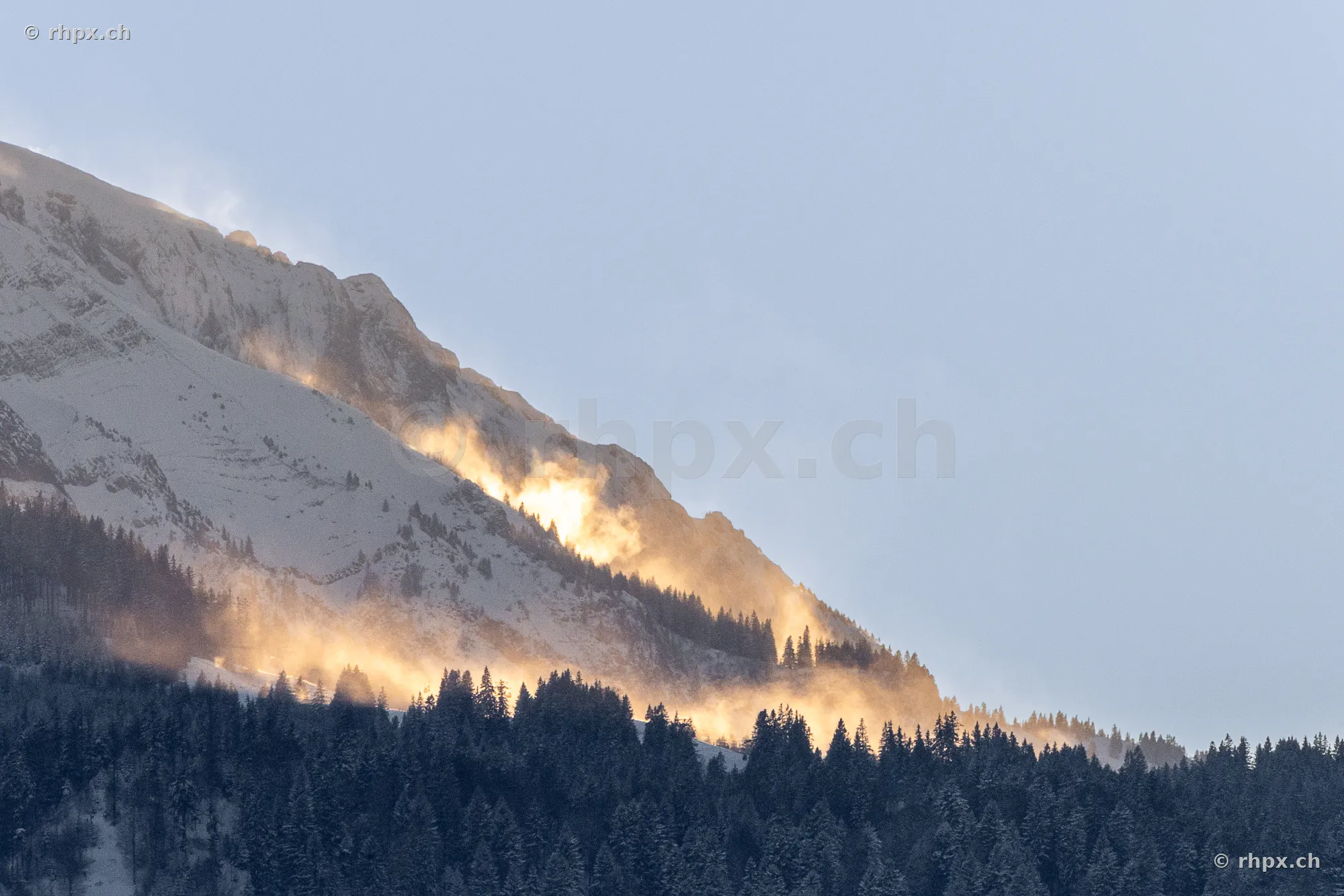 Verschneiter Berghang des Pilatus im goldenen Licht mit Wald und Nebelschwaden