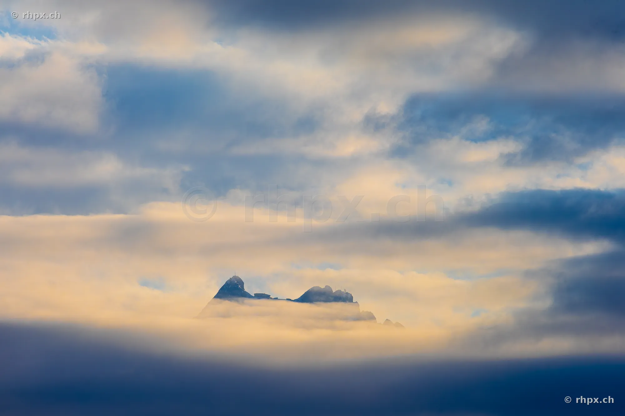 The peaks of Mount Pilatus emerging from a dense layer of clouds