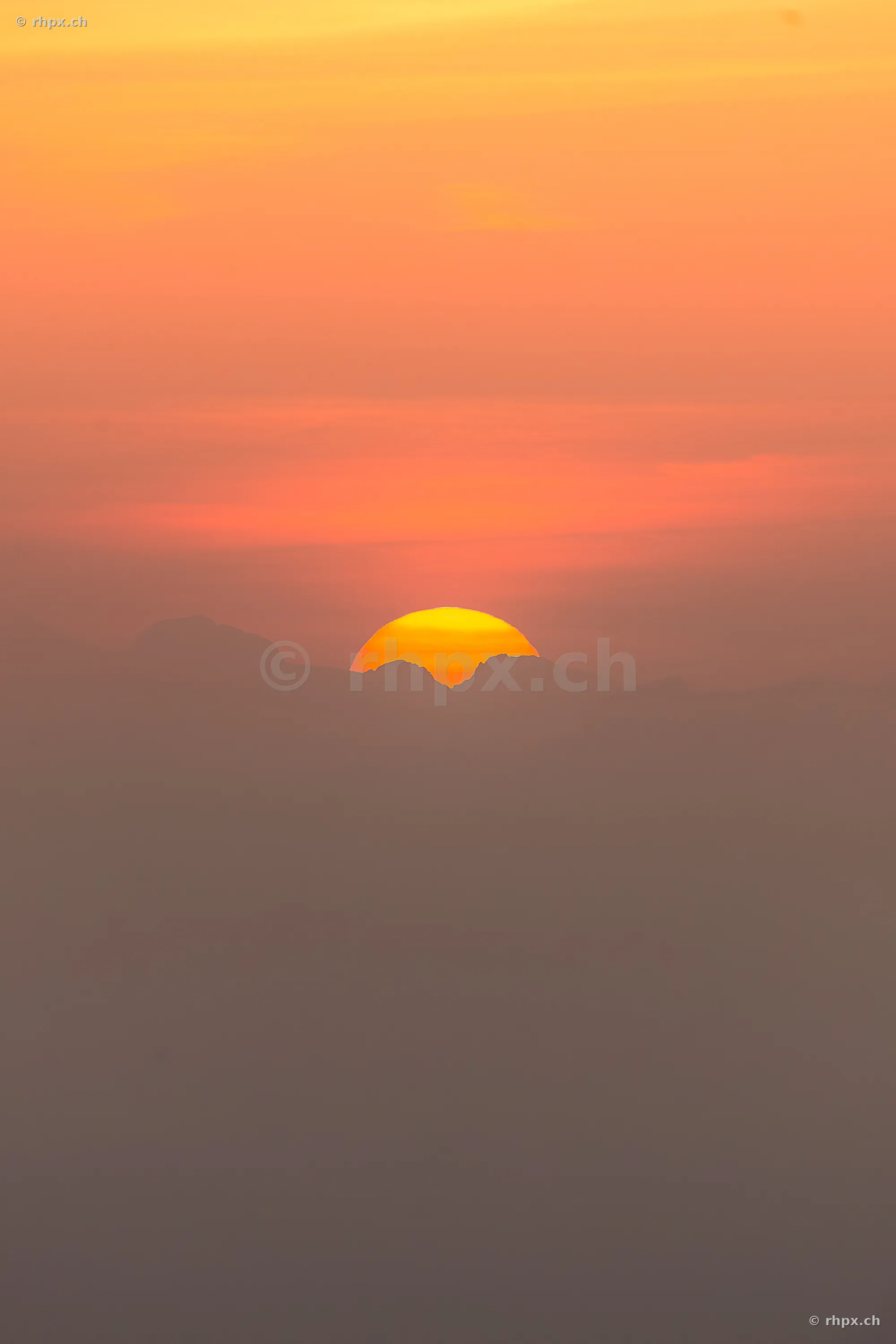 The setting sun dips behind the silhouettes of Mount Pilatus in Central Switzerland