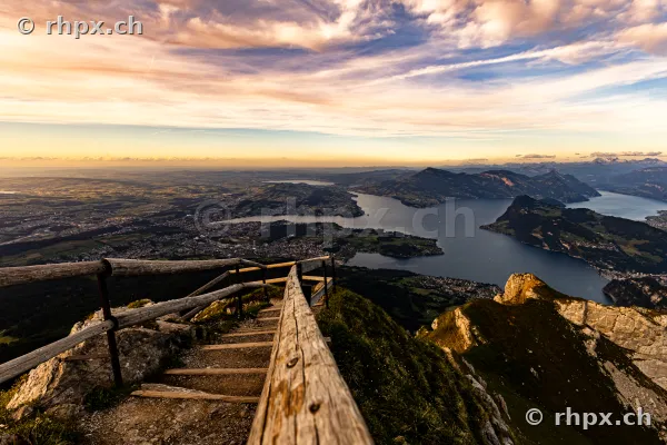 Blick von einem Holzgeländer auf dem Pilatus über den Vierwaldstättersee bei Sonnenuntergang
