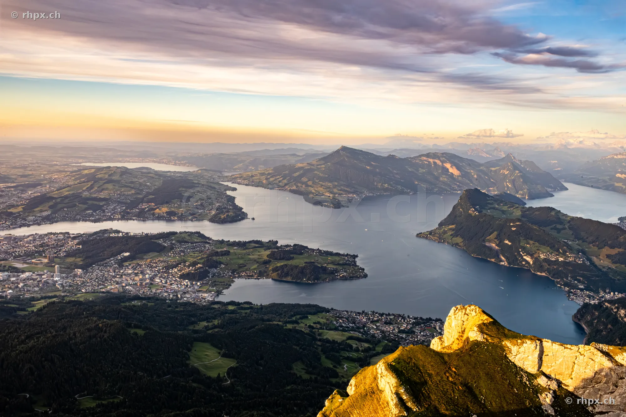 Aerial view from Mount Pilatus overlooking Lake Lucerne and the surrounding alpine landscape in evening light.