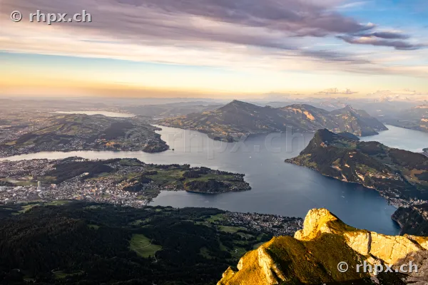 Luftaufnahme vom Pilatus mit Blick über den Vierwaldstättersee und die umliegende Alpenlandschaft bei Abendlicht.
