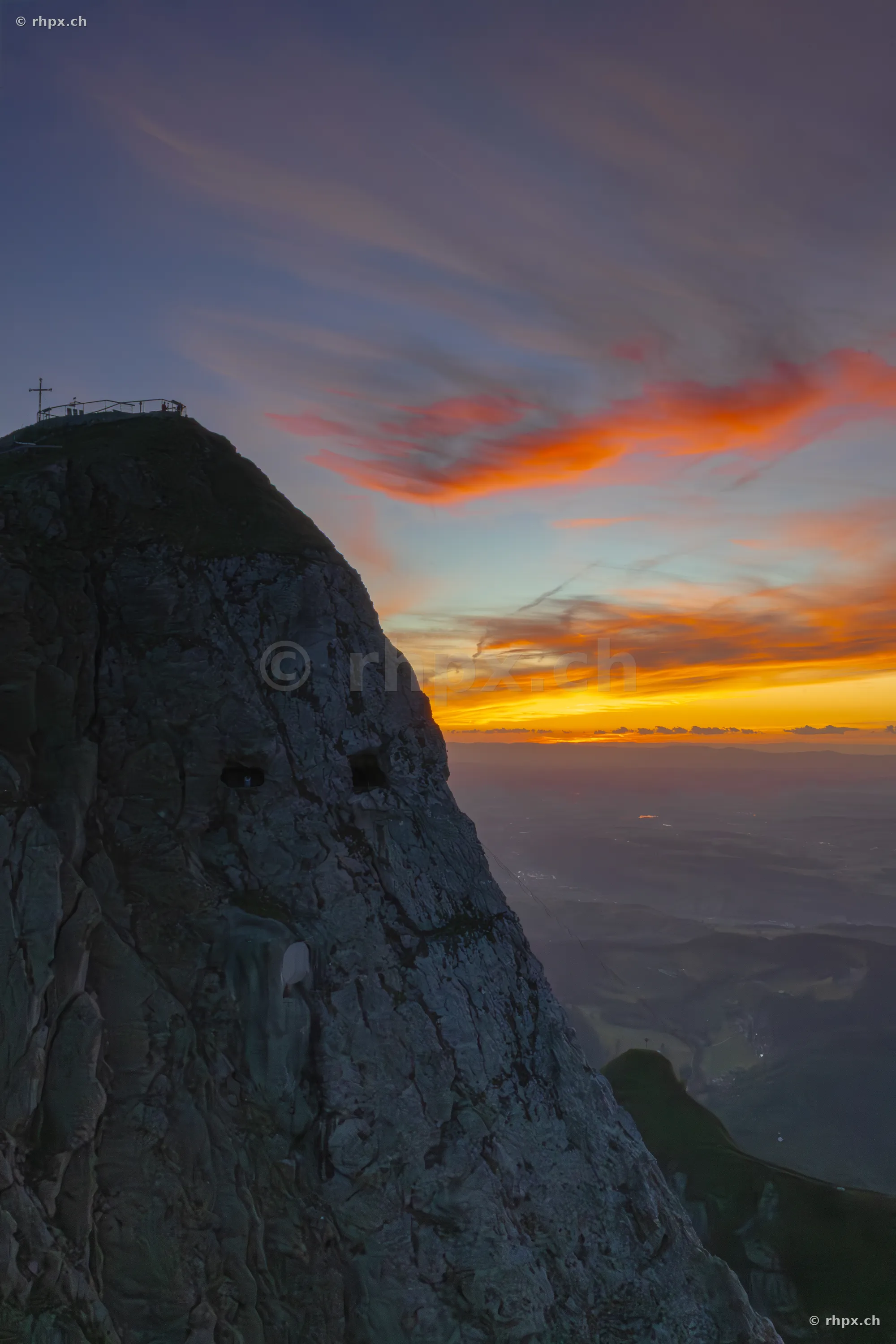 View of the Pilatus summit near Lucerne during a sunset with orange and red clouds.