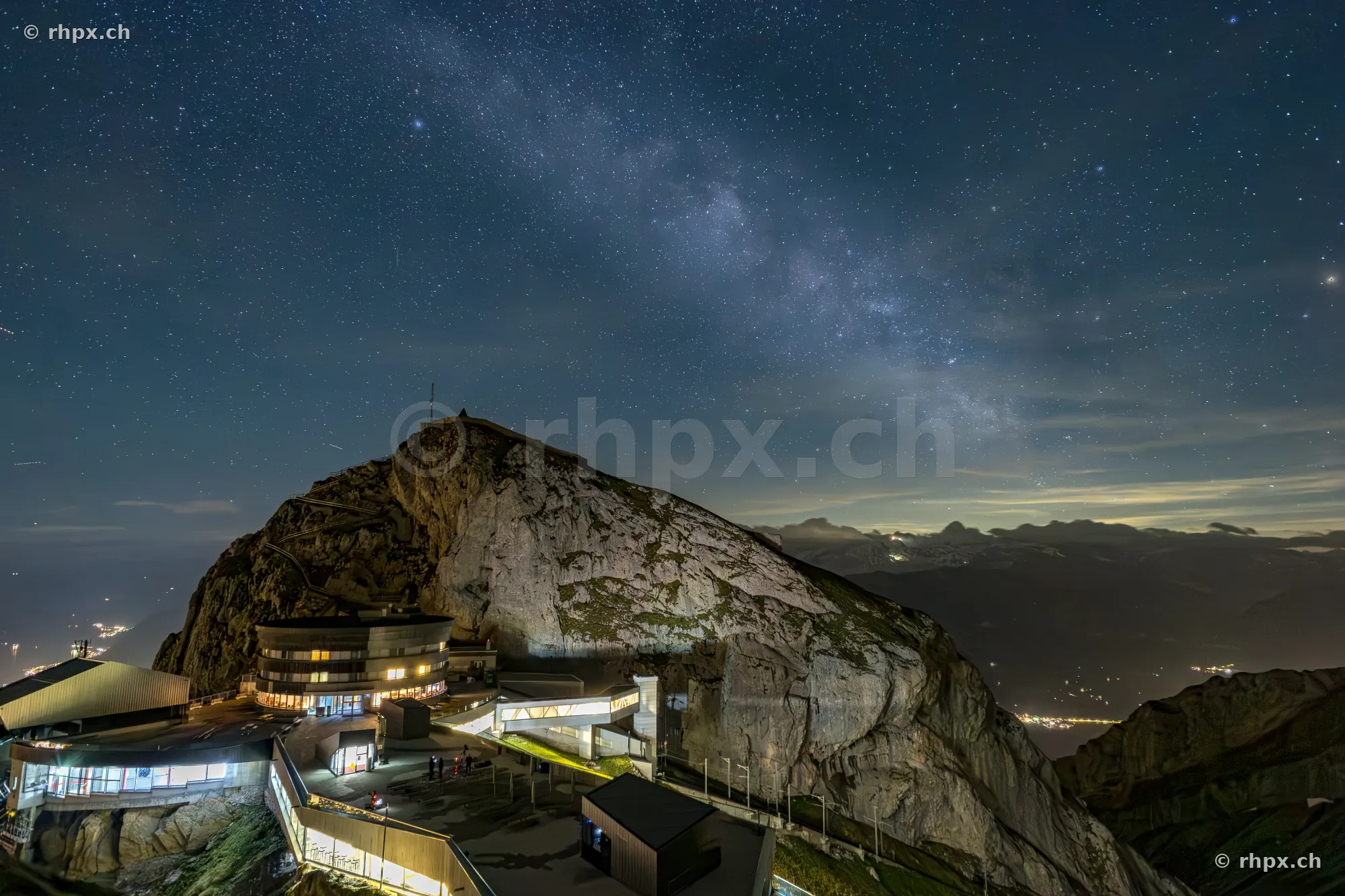 Nächtliche Ansicht des Gipfelbereichs vom Pilatus mit beleuchteten Gebäuden unter einem Sternenhimmel mit Milchstrasse