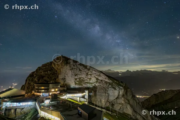 Nächtliche Ansicht des Gipfelbereichs vom Pilatus mit beleuchteten Gebäuden unter einem Sternenhimmel mit Milchstrasse