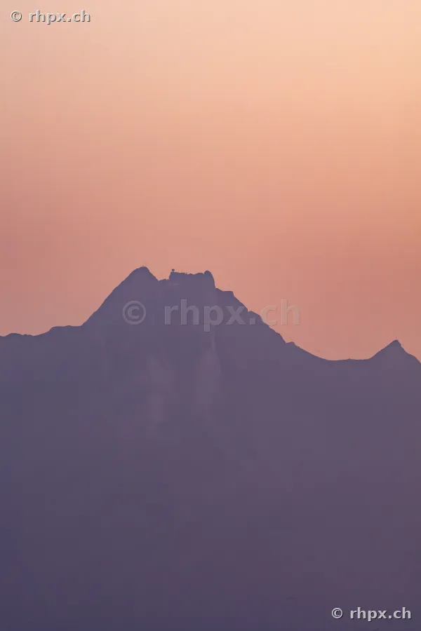 Dark silhouette of Mount Pilatus against a softly colored evening sky