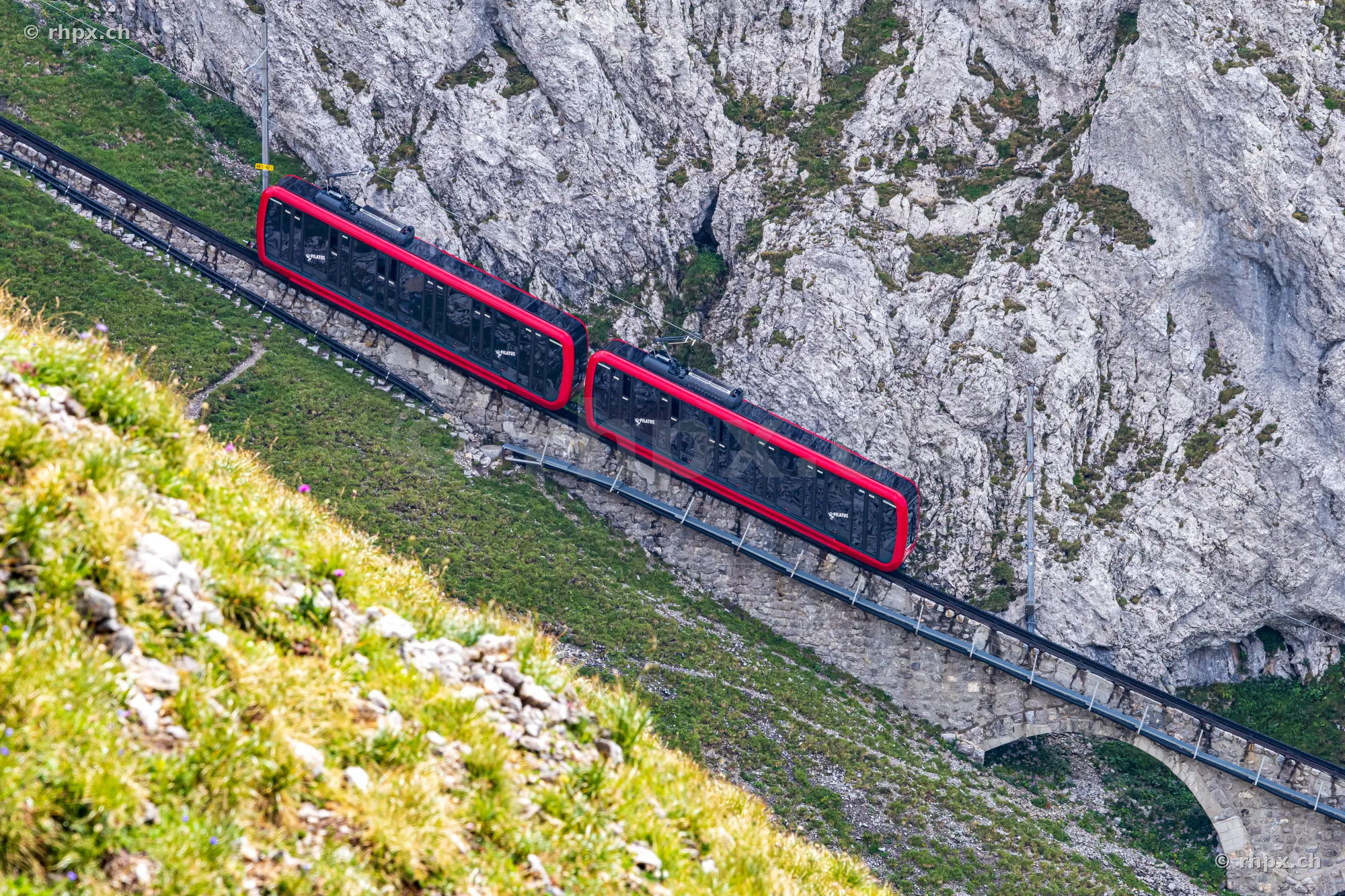 The red Pilatus cogwheel train travels through the steep rocky landscape of Mount Pilatus.