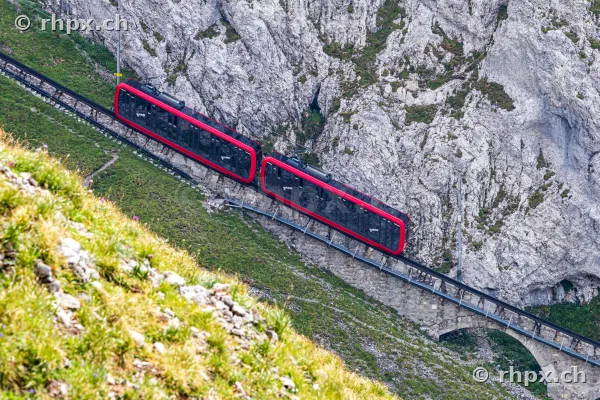 The red Pilatus cogwheel train travels through the steep rocky landscape of Mount Pilatus.