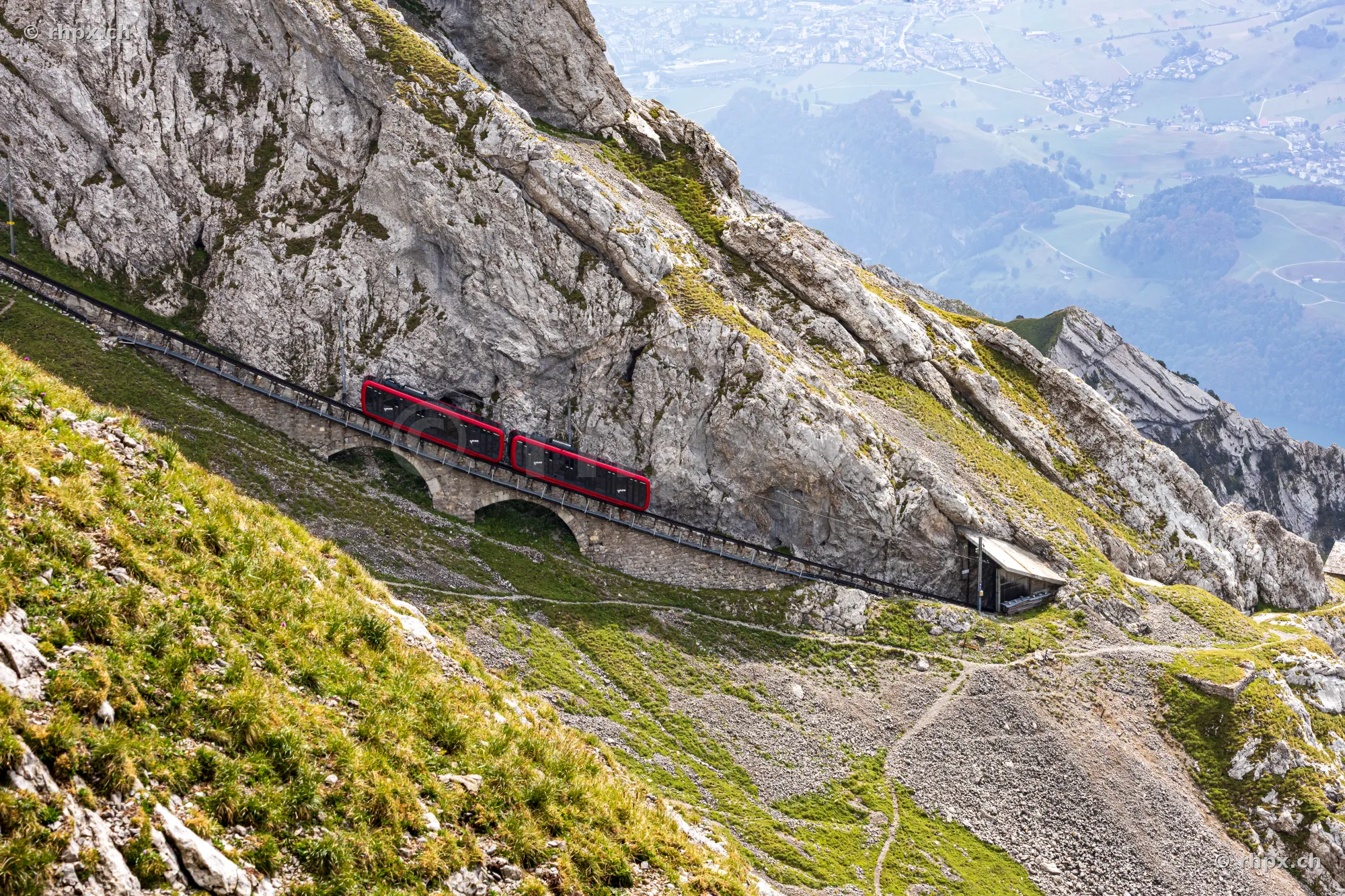 Red Pilatus cogwheel train travelling through the steep rock face of Mount Pilatus.