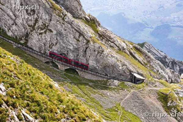 Red Pilatus cogwheel train travelling through the steep rock face of Mount Pilatus.