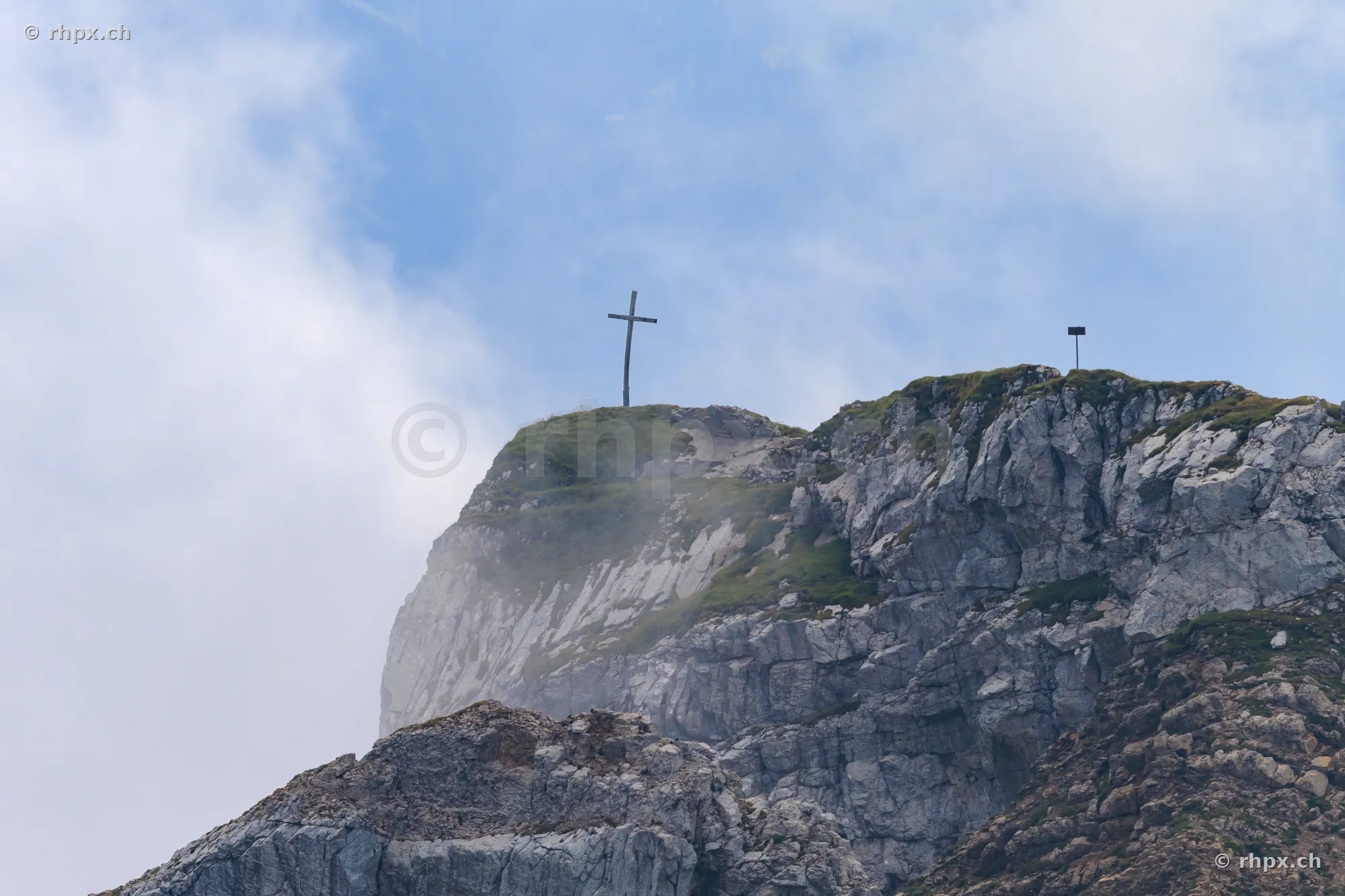 Das Gipfelkreuz auf dem Pilatus umgeben von Wolken und Felsen
