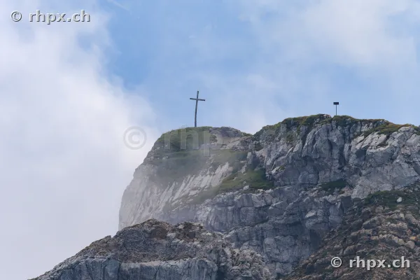 The summit cross on Mount Pilatus surrounded by clouds and rocks
