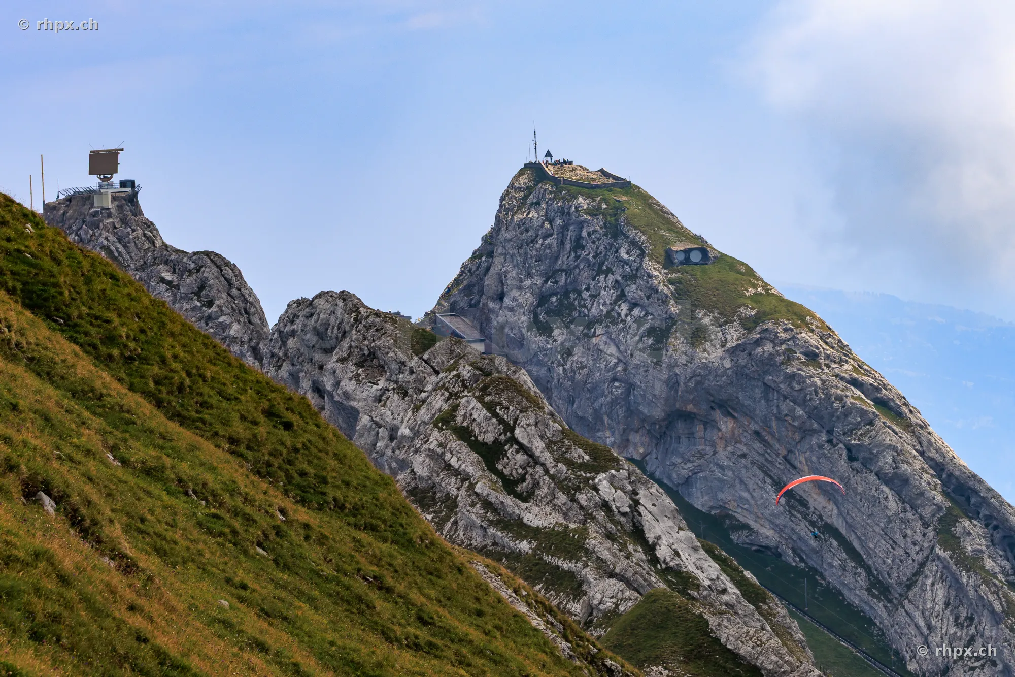 View of the rock formations at the summit of Mount Pilatus with a paraglider flying by